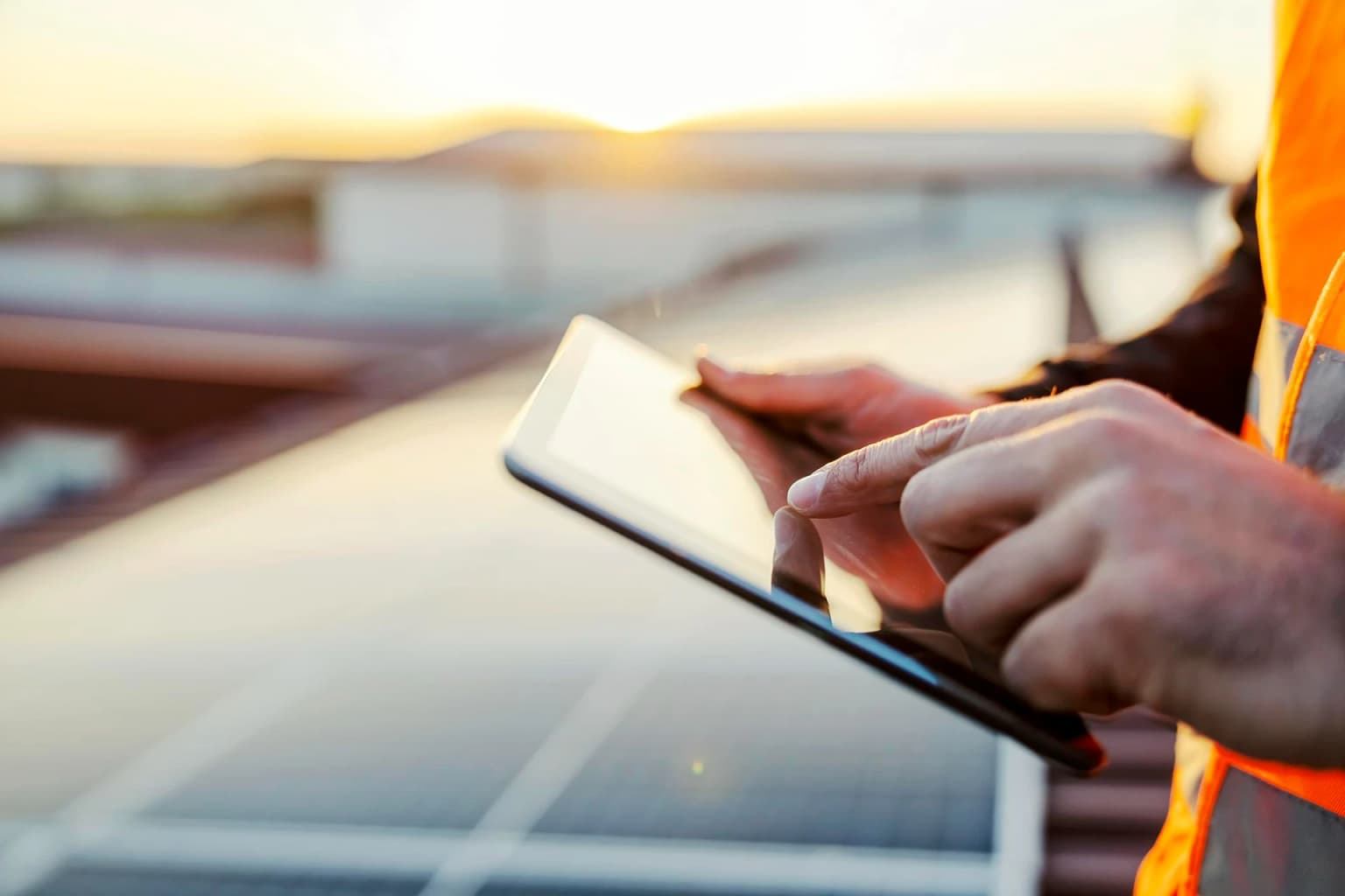 Technicien sur toiture solaire vérifiant une installation sur tablette, lumière de soleil couchant